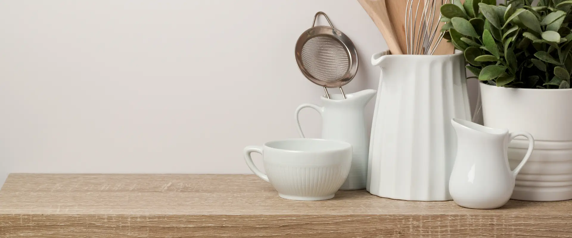 White kitchenware and plant on a wooden shelf