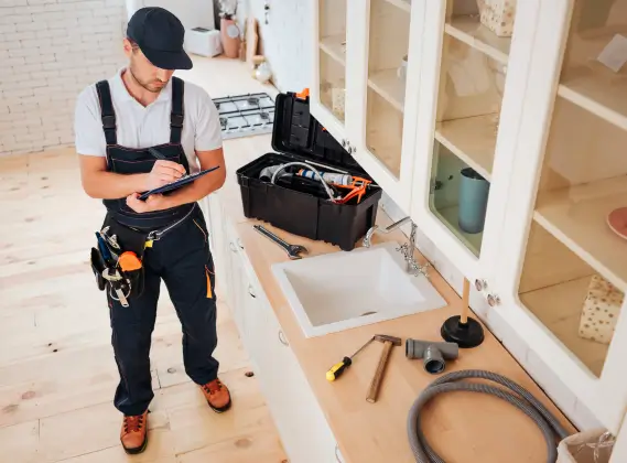 Man in a plumber's uniform filling out a checklist