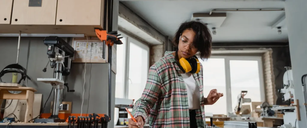 Woman in a workshop writing on a blueprint