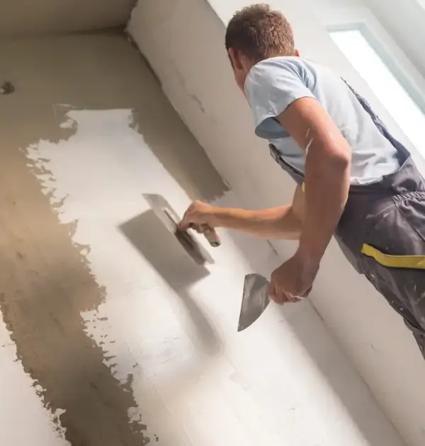 Handyman plastering an interior wall with trowel tool