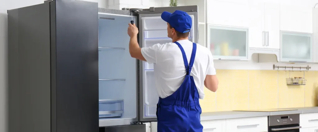 Professional handyman fixing a refrigerator in London — expert appliance repair by The Handy Home Pro.